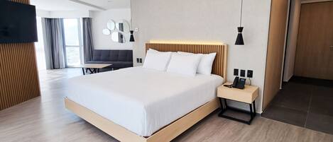 A modern hotel room with a large bed, bedside table, and a TV mounted on the wall.