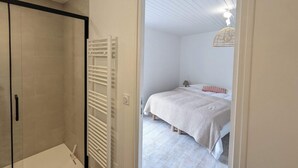 Un dormitorio con cama, lámpara de noche y lámpara colgante.