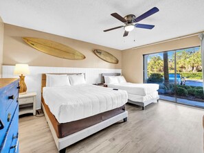A hotel room with a large bed, two bedside tables, a ceiling fan, and a view of the outdoors. - Edgewater Golf Villa 3204 (Panama City Beach)