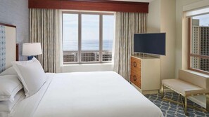 A hotel room with a large bed, a TV, a desk, and a view of the city. - 2 Bedroom Premier (2BX) at Grand Waikikian, a Hilton Grand Vacations Club (Honolulu)