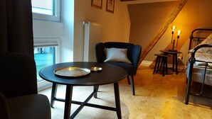 A cozy room with a round table, a chair, a bed, and a staircase. - The Village Island - Över de Deel (Trebel)