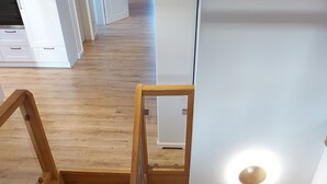 A wooden staircase with a glass railing leading to a white door. - The Village Island - Över de Deel (Trebel)
