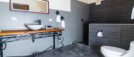 A modern bathroom with a wooden vanity, a large mirror, a white sink, and a toilet.
