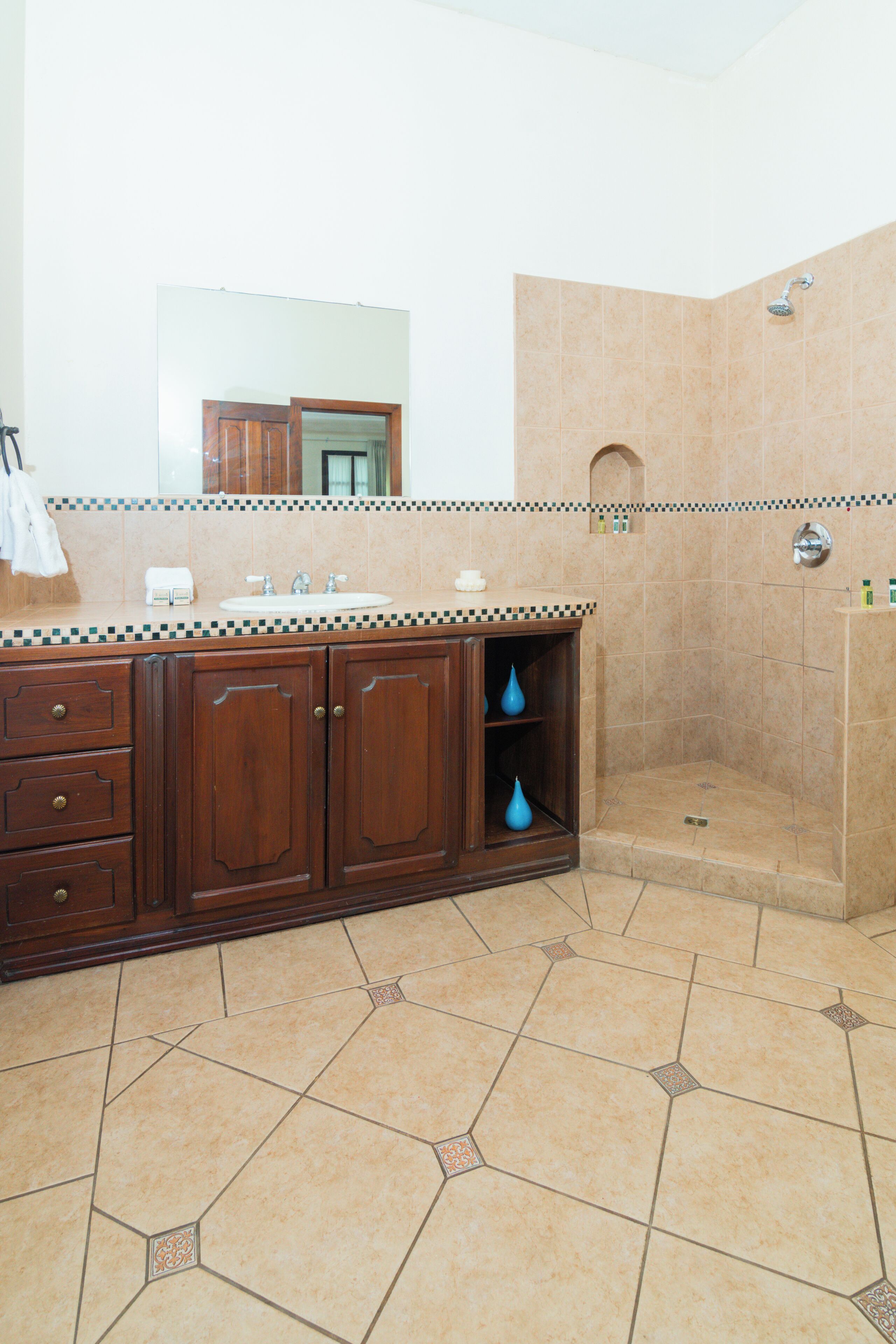 A bathroom with a wooden vanity, a sink, and a shower area.