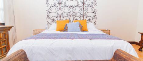 A bed with a white bedspread, two orange pillows, and a decorative headboard.