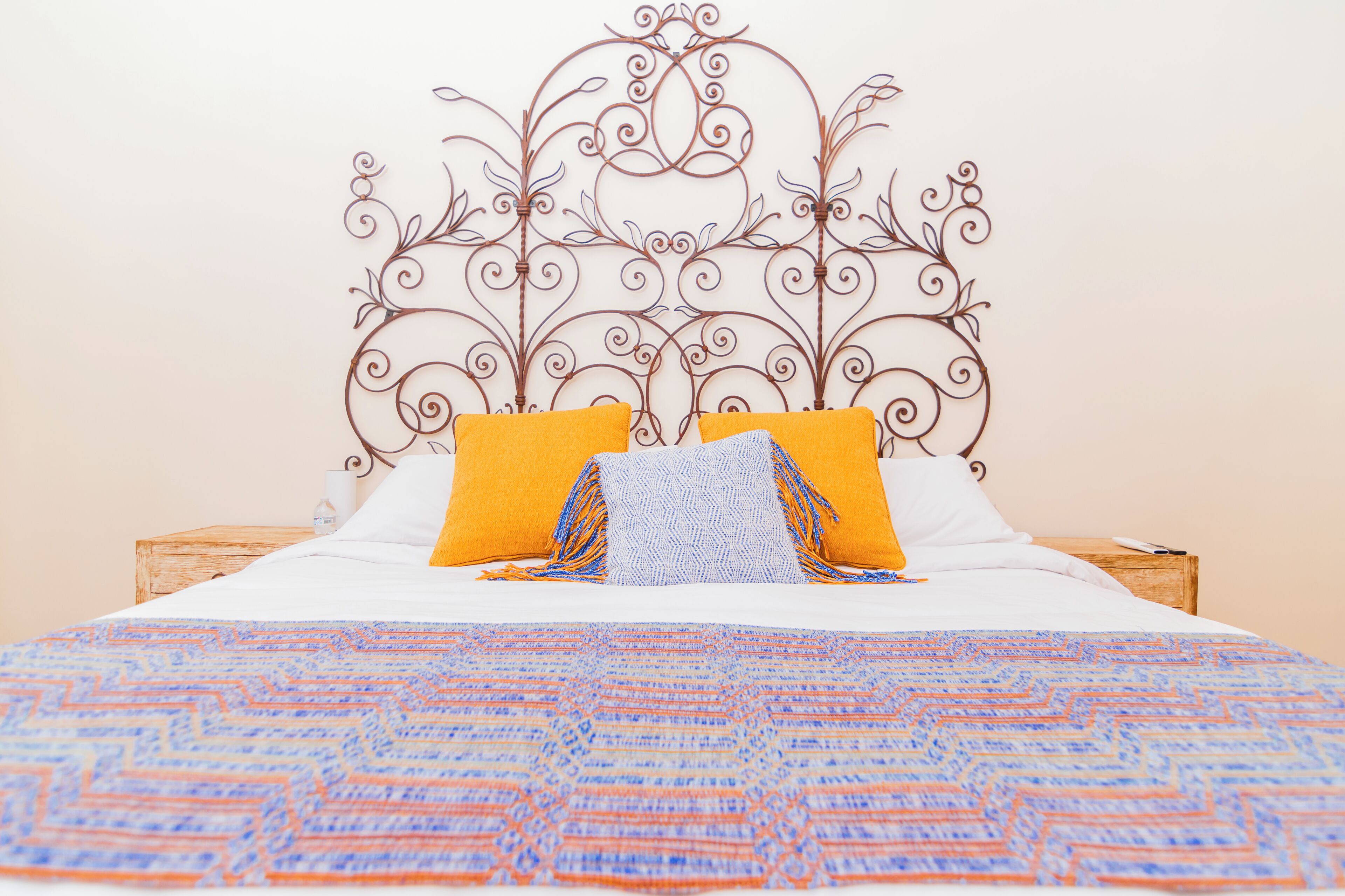 A bed with a patterned bedspread, two pillows, and a decorative metal headboard.