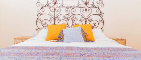 A bed with a patterned bedspread, two pillows, and a decorative metal headboard.