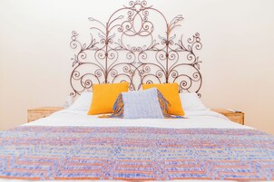 A bed with a patterned bedspread, two pillows, and a decorative metal headboard.