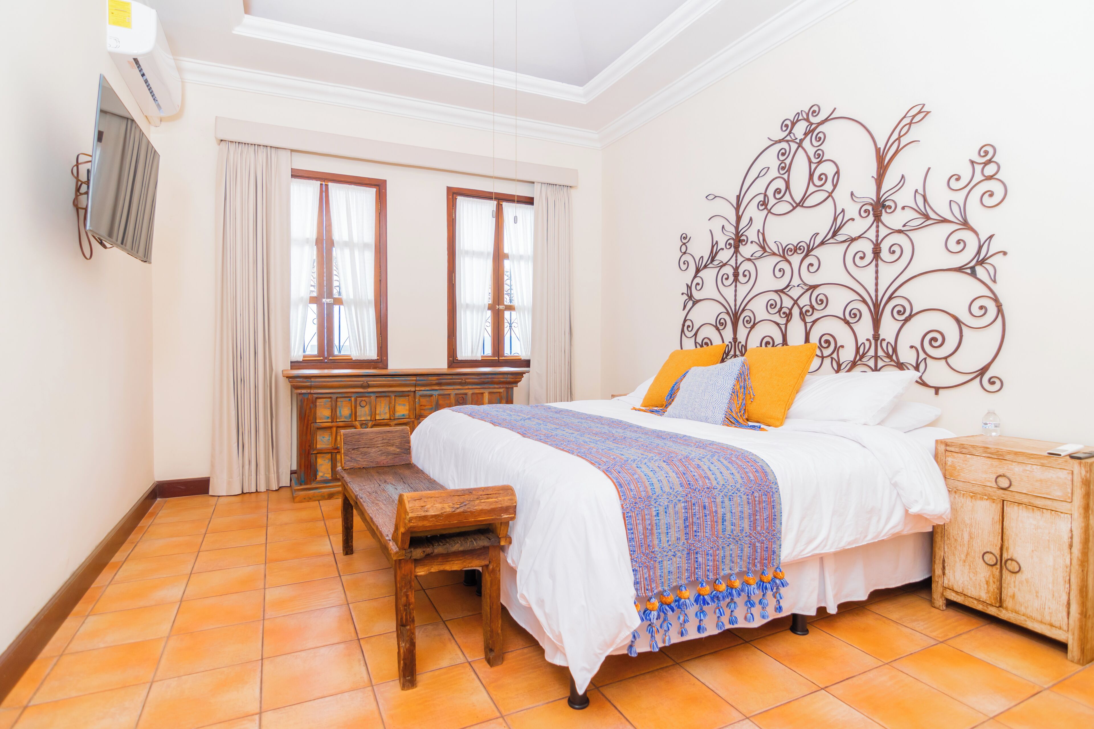 A bedroom with a bed, wooden bench, bedside table, and a decorative wall piece.