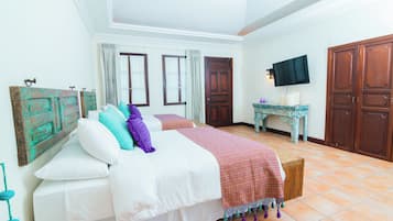 A bedroom with a bed, curtains, a television, and wooden furniture.