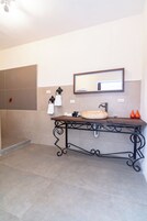 Un baño con lavamanos, espejo y perchero para toallas.
