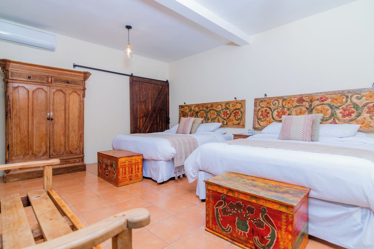 A bedroom with two beds, a wooden wardrobe, and a bench.