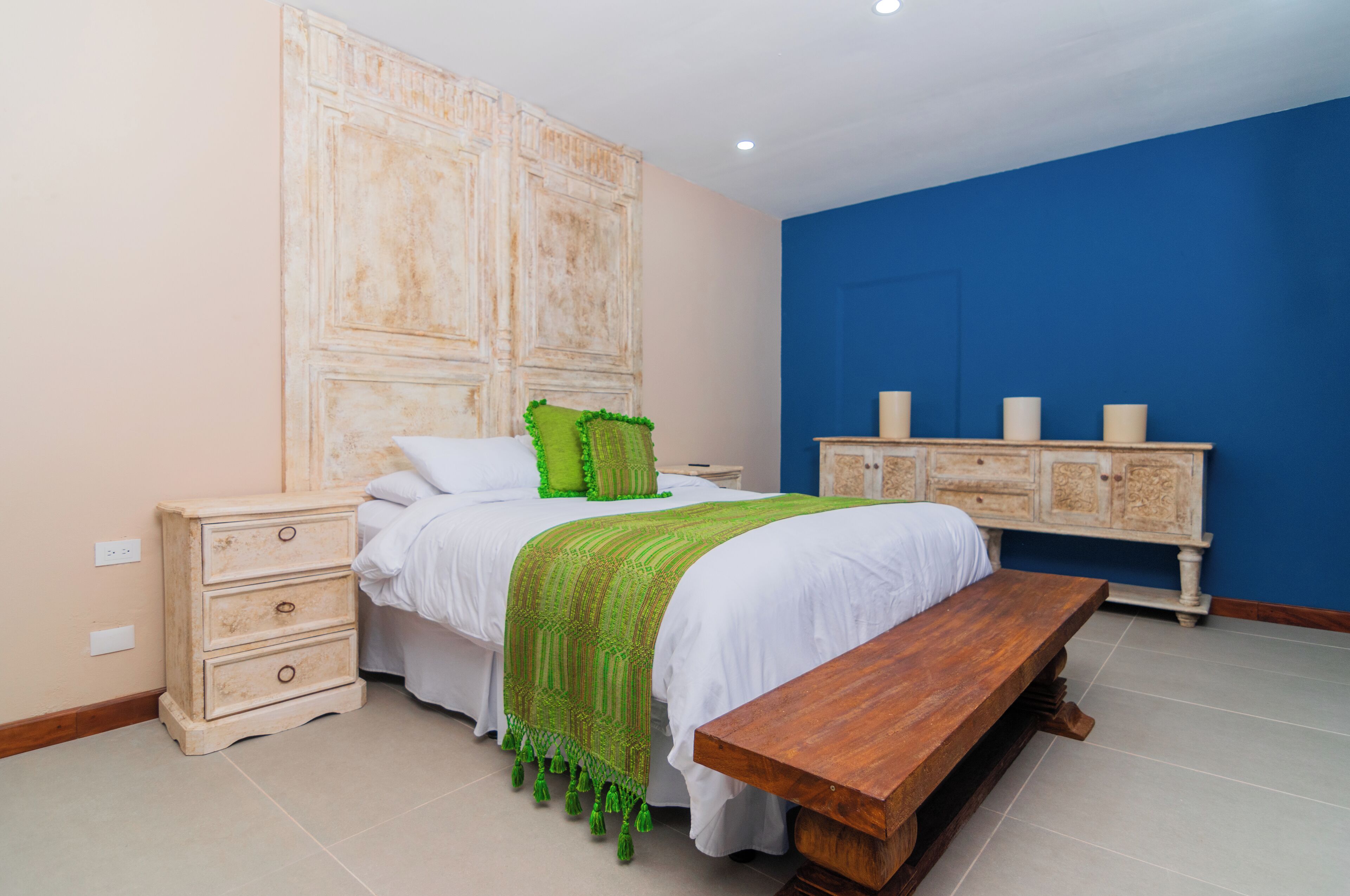 A bedroom with a bed, bedside tables, a bench, and a cabinet.