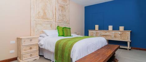 A bedroom with a bed, bedside tables, a bench, and a cabinet.