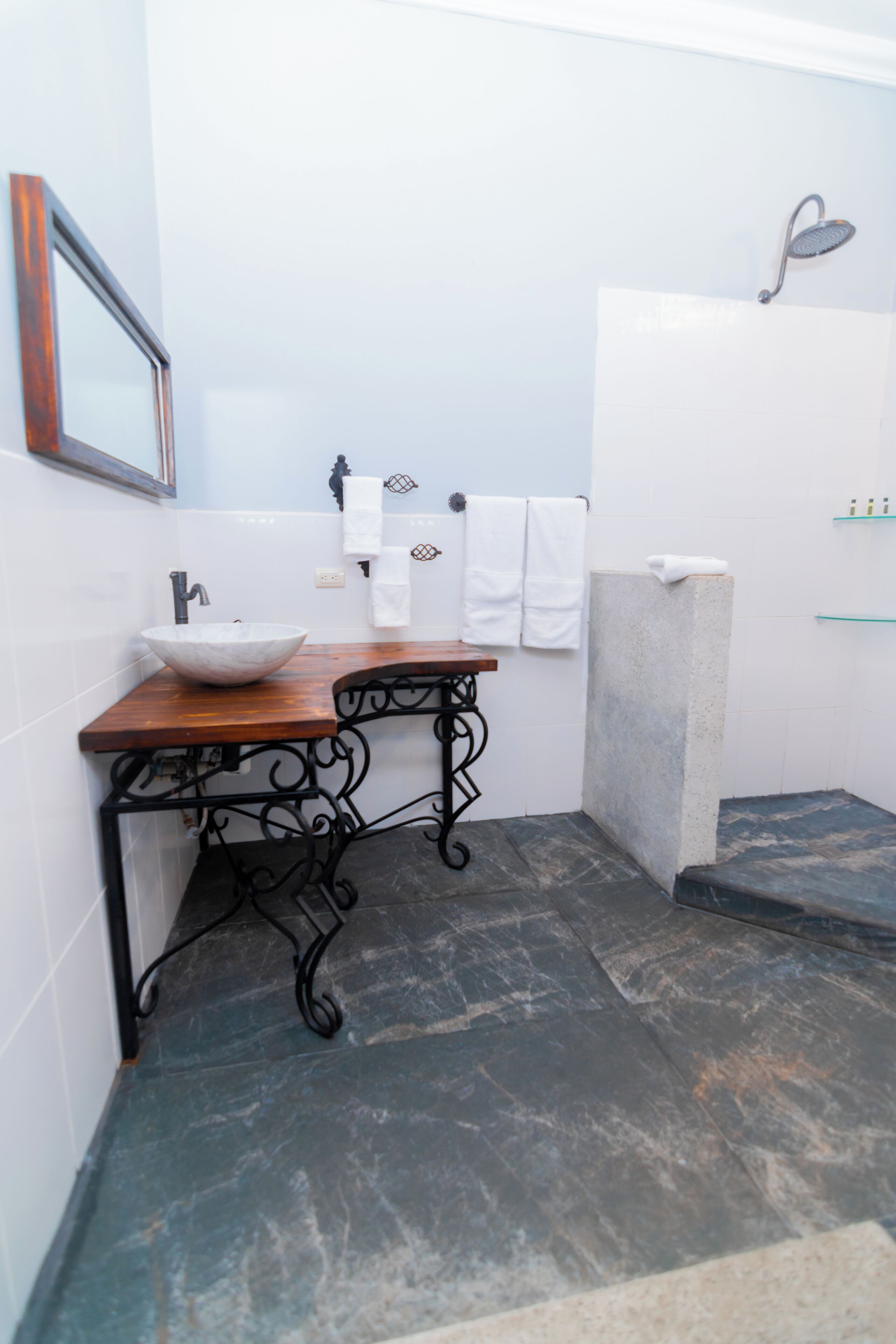 A bathroom with a wooden vanity, a white sink, and a shower area.
