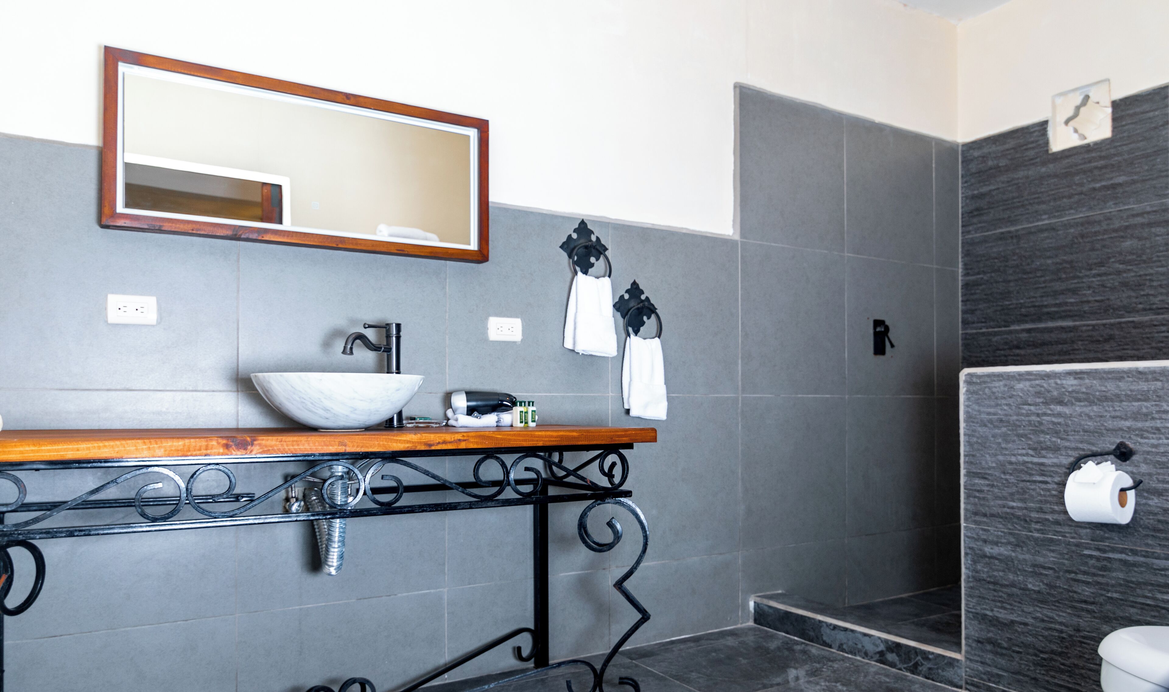 Une salle de bain avec un meuble-lavabo en bois, un lavabo blanc, un miroir et un porte-serviettes.