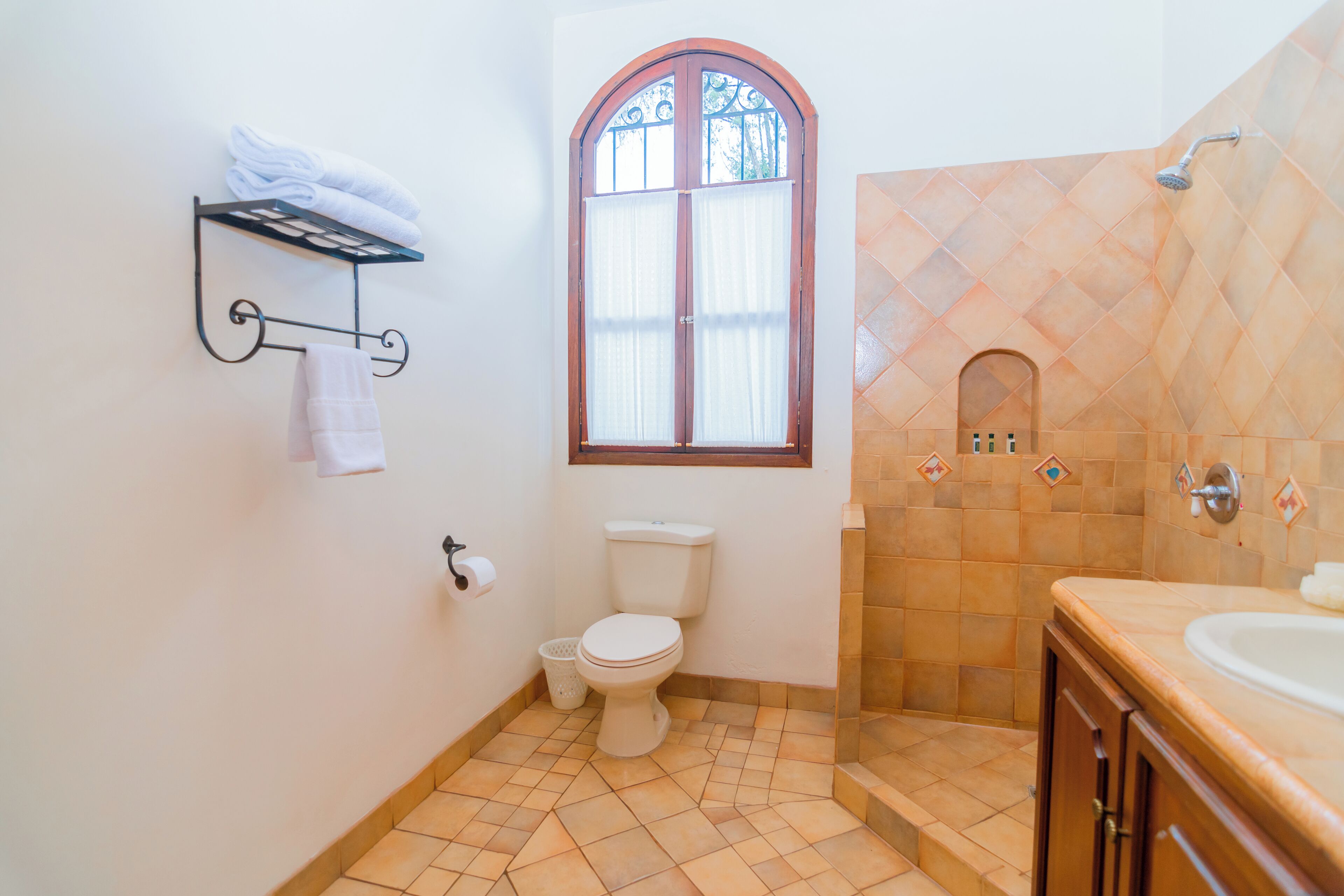 Ein Badezimmer mit Toilette, Fenster, Dusche und Waschbecken.