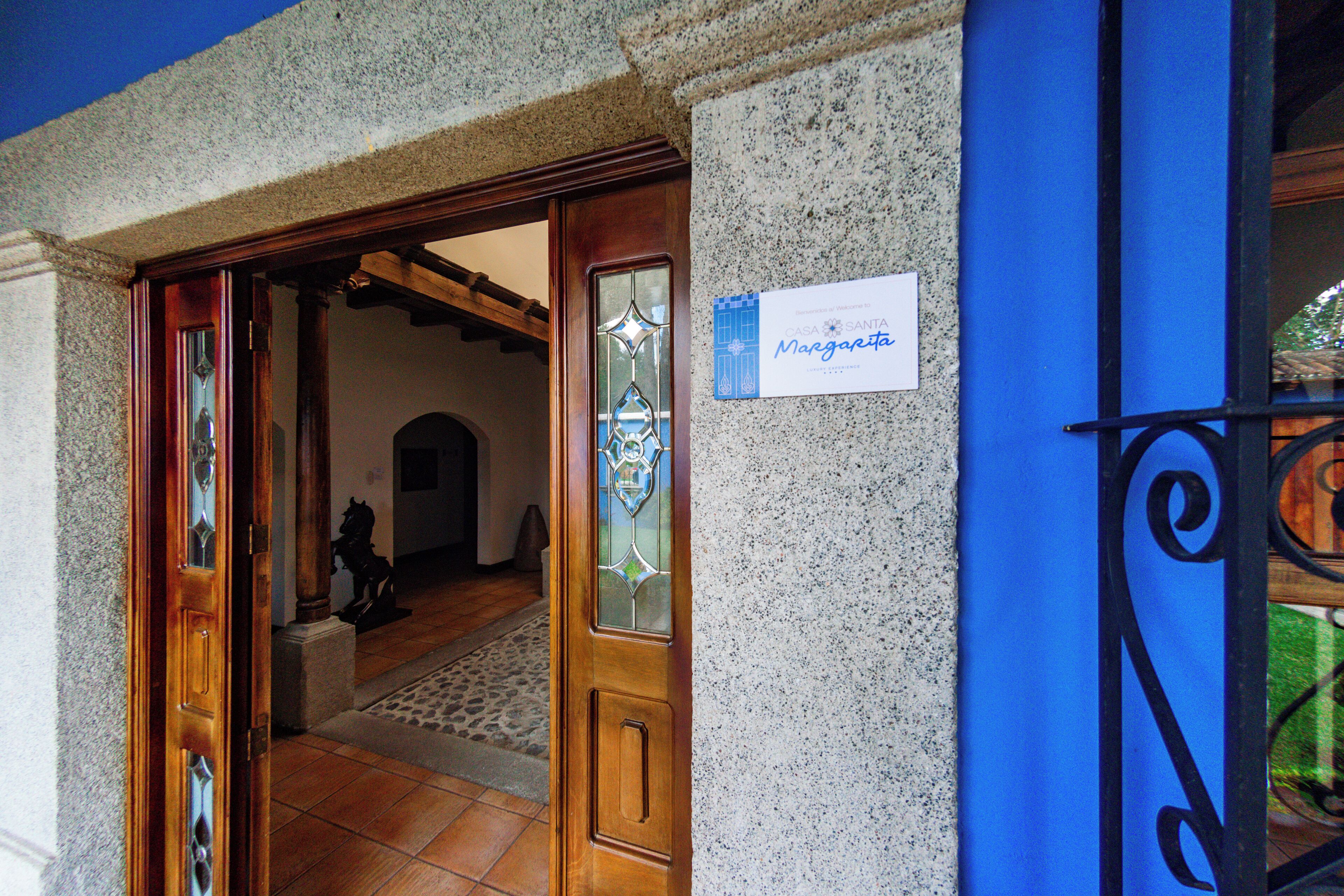 L’entrée d’un hôtel, avec une porte en bois, une enseigne indiquant « Casa Santa Margarita » et un mur en pierre.