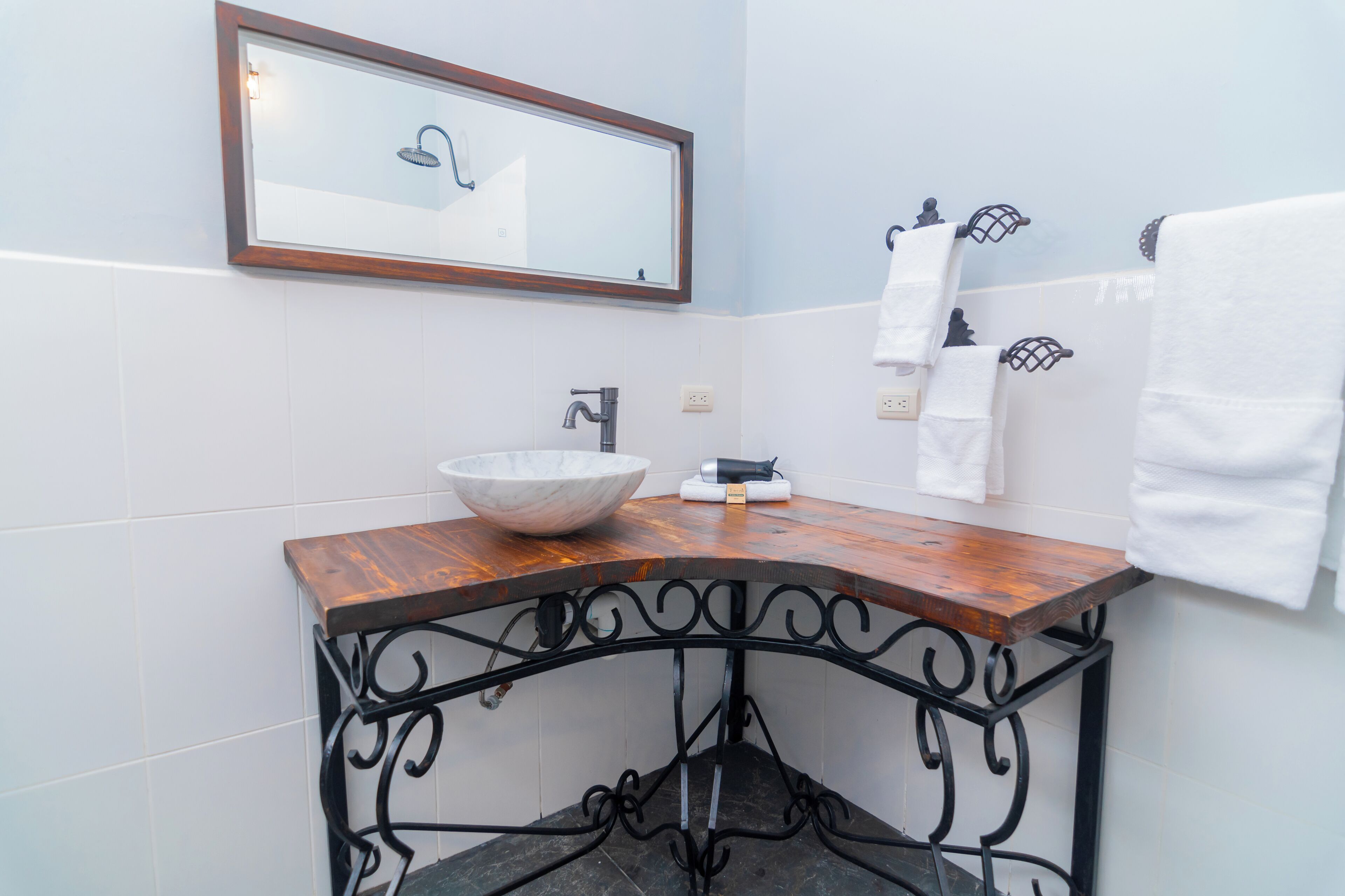 A bathroom with a wooden vanity, a large mirror, a white sink, and a towel rack.