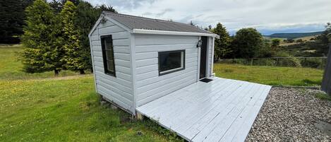 A small, single-story shed with a sloped roof and a wooden deck.