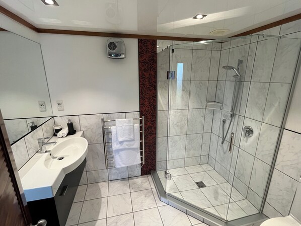 A modern bathroom with a glass-enclosed shower, a sink, and a towel rack. - Greenwood Homestead (Tarara)