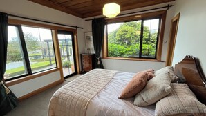 A bedroom with a large bed, a wooden ceiling, and a view of greenery outside. - Greenwood Homestead (Tarara)