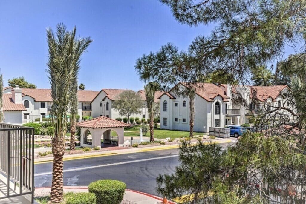 A residential area with multi-story buildings, a gated entrance, and a clear sky.