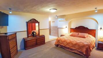 A bedroom with a bed, dresser, mirror, and ceiling lights.