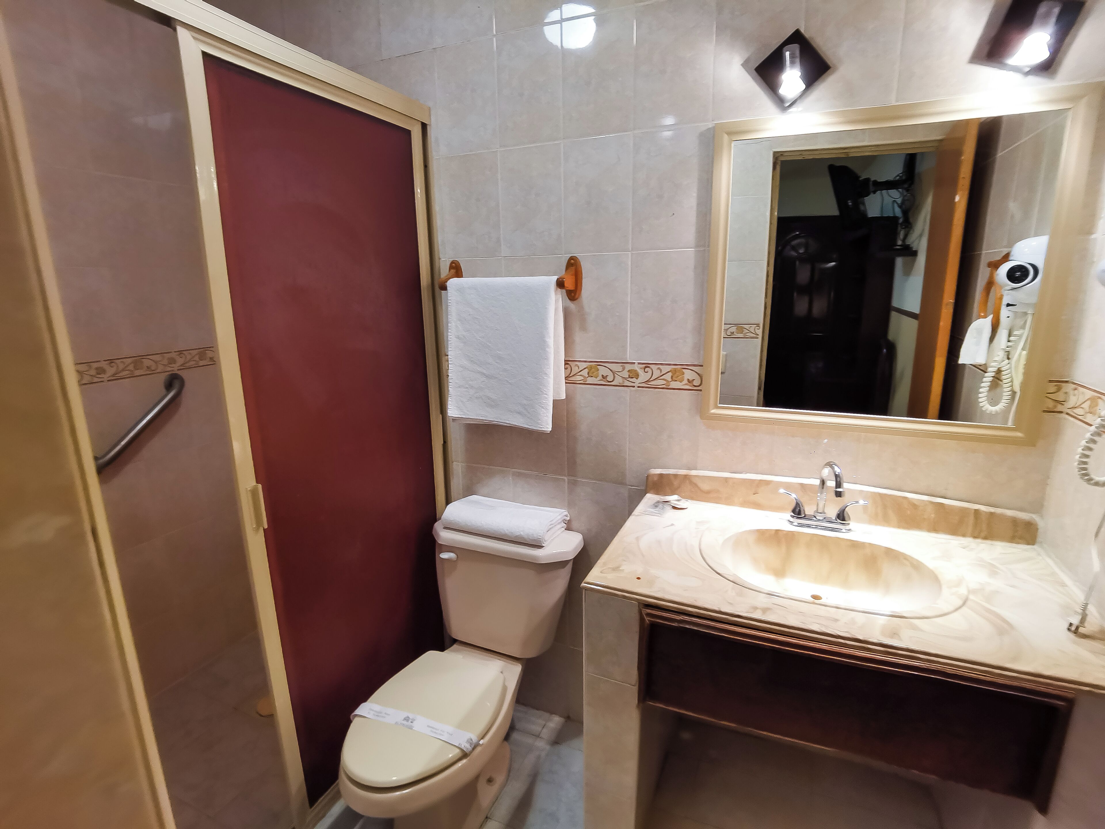 Un baño con inodoro, lavamanos y espejo.