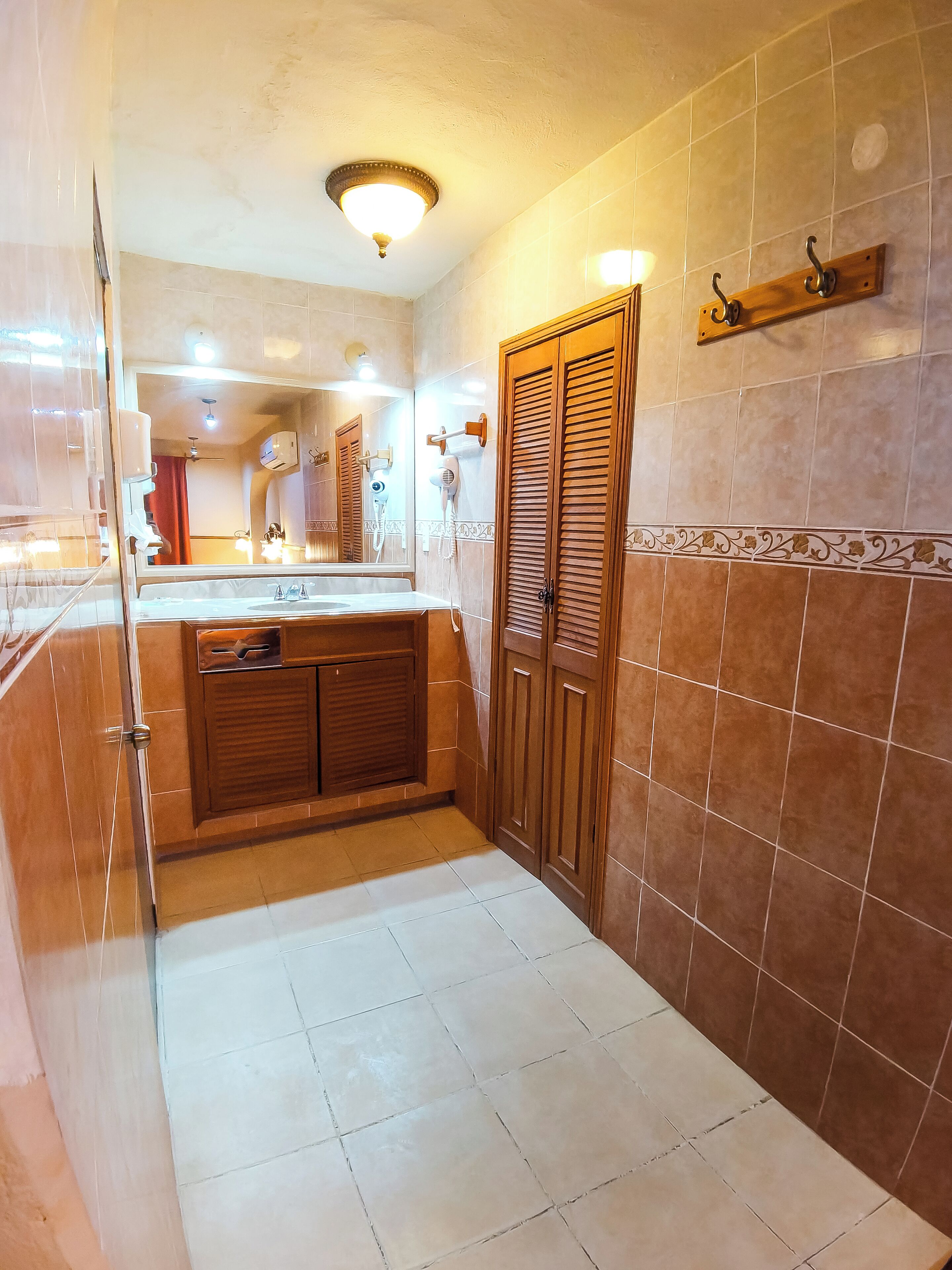 A bathroom with a sink, mirror, towel rack, and a shower area.