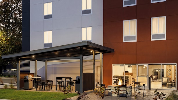 A modern building with a covered outdoor seating area, a barbecue grill, and a fire pit.