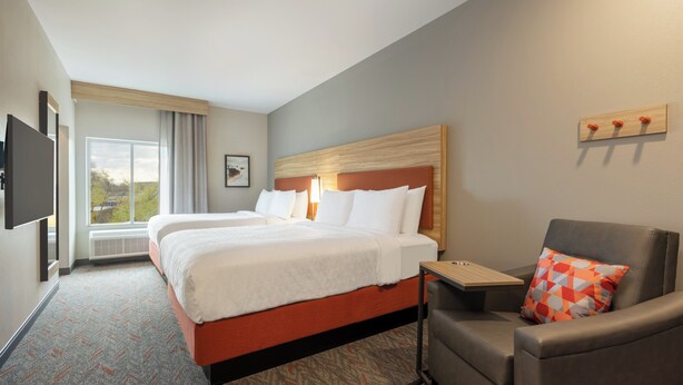 A hotel room with a large bed, a desk, a chair, and a TV mounted on the wall. - Candlewood Suites Coralville Iowa City by IHG (Coralville)