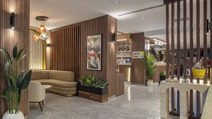 A modern lobby with a seating area, a Carrer Shop, and a bar area with a yellow lamp. - Garner Hotel Istanbul - Airport Arnavutkoy by IHG (Arnavutköy)