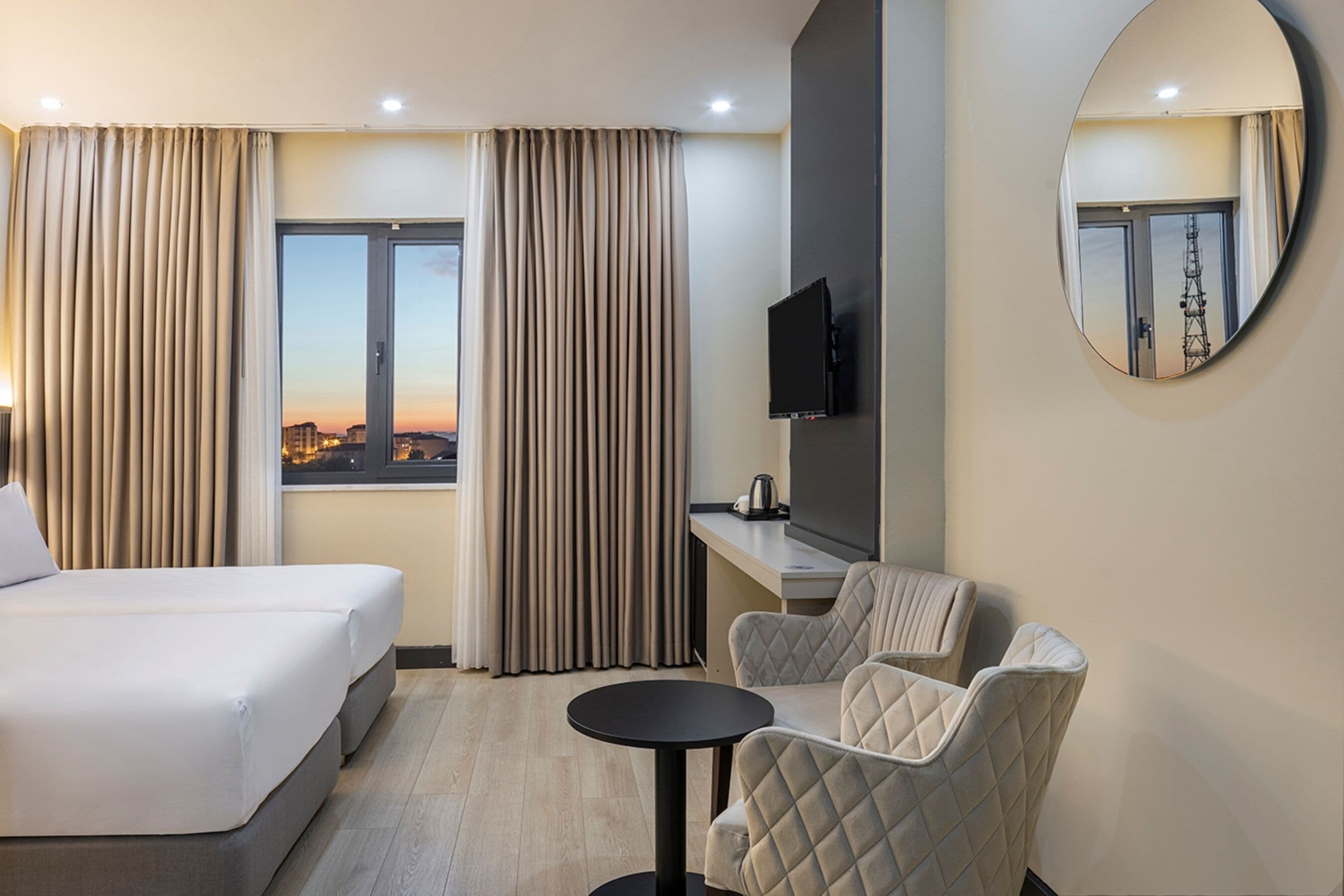 Une chambre d’hôtel avec un lit, un bureau et une chaise, une télévision et une vue sur le paysage urbain.