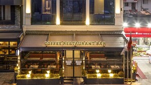A hotel with a modern facade, a coffee restaurant bar at the ground level, and a prominent entrance with a decorative arch. - Garner Hotel Istanbul - Airport Arnavutkoy by IHG (Arnavutköy)