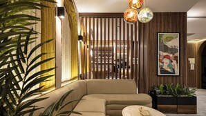 A modern interior with a beige sectional sofa, a round coffee table, and a wooden partition with vertical slats. - Garner Hotel Istanbul - Airport Arnavutkoy by IHG (Arnavutköy)