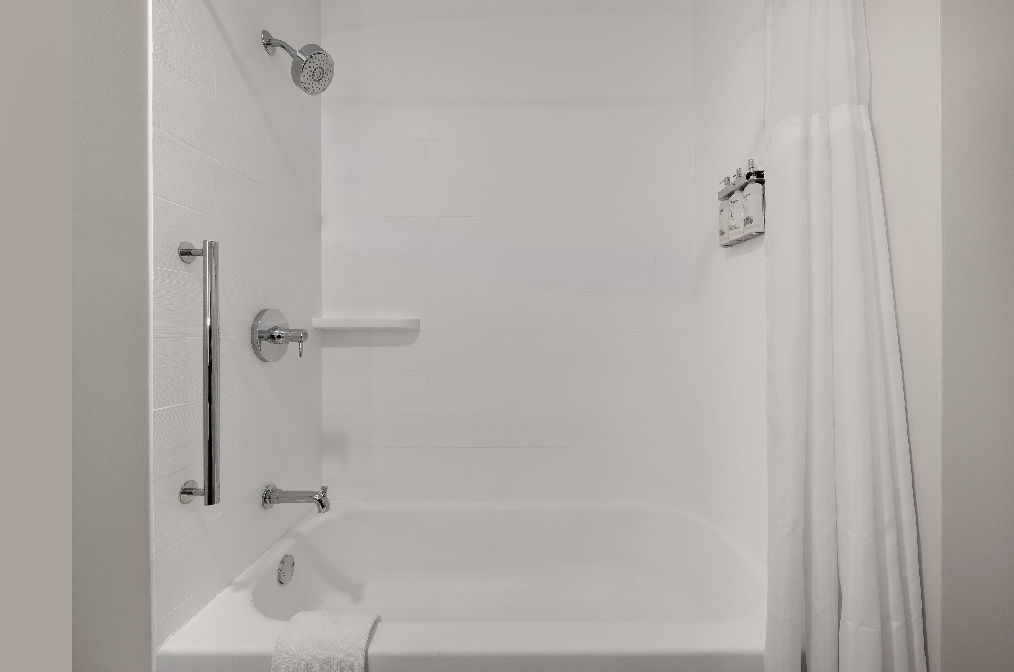 Een moderne badkamer met een bad, douche en toilet.