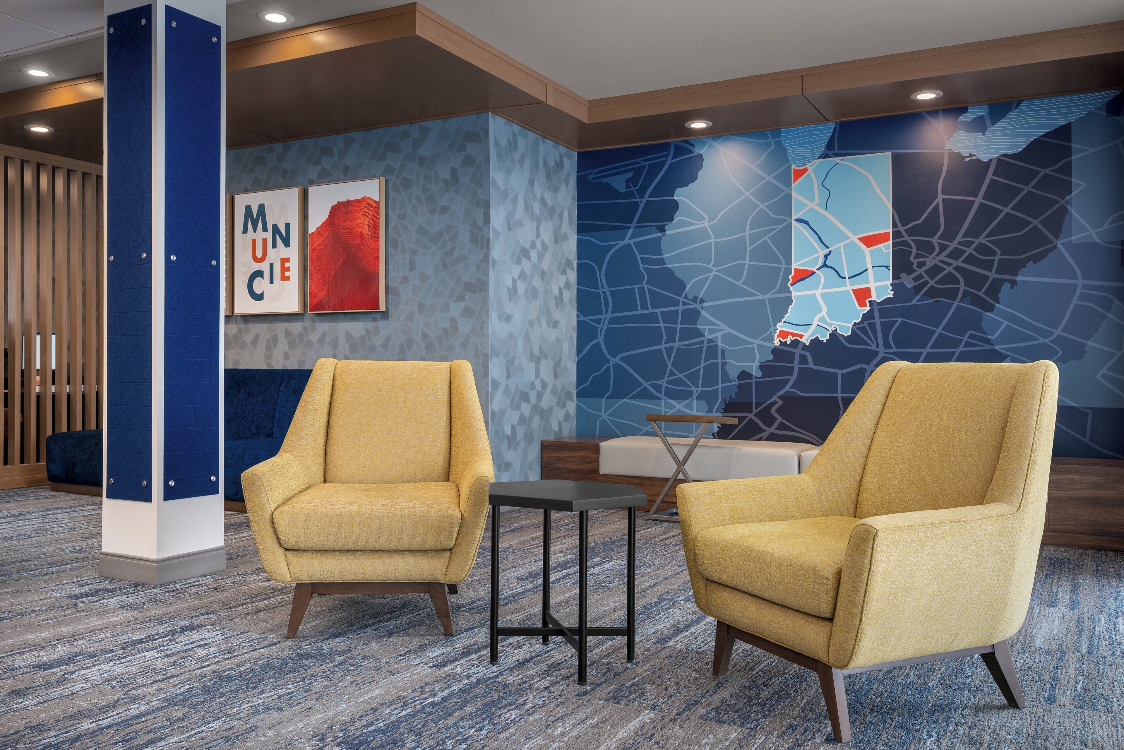 A lobby with two yellow armchairs, a small table, and a map mural on the wall.