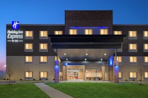Egy modern dizájnnal rendelkező Holiday Inn Express szálloda, melynek feltűnő bejárata, számos ablaka és gondozott előkertje van.