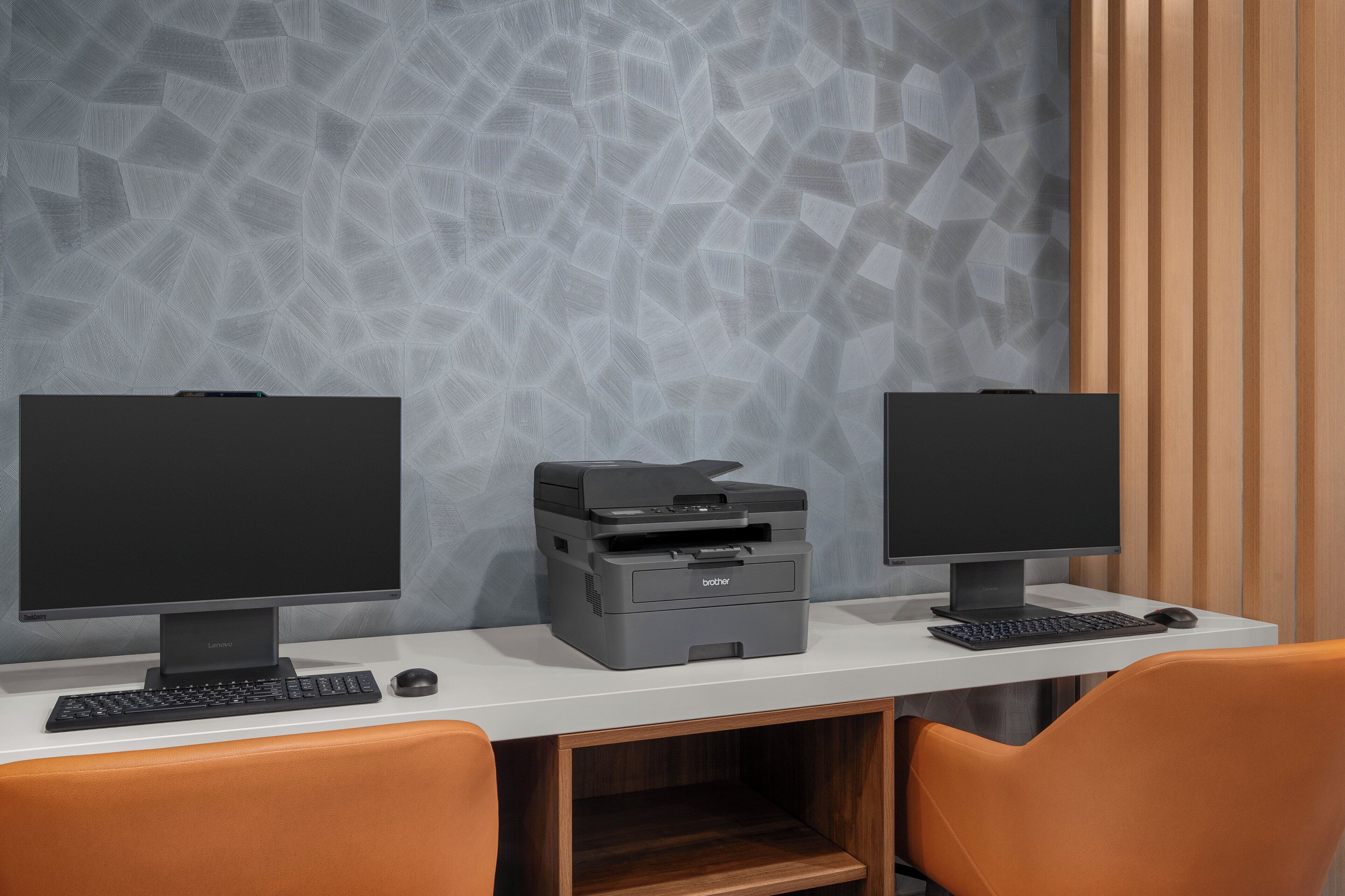 Een werkplek met twee monitoren, een printer en een toetsenbord op een wit bureau.