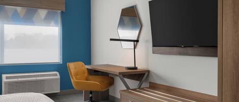 A modern room with a bed, a desk with a chair, a TV, and a heater.