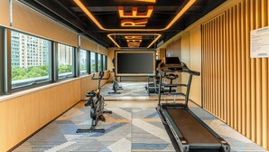 Een moderne sportschool met loopbanden, hometrainers en een groot scherm.