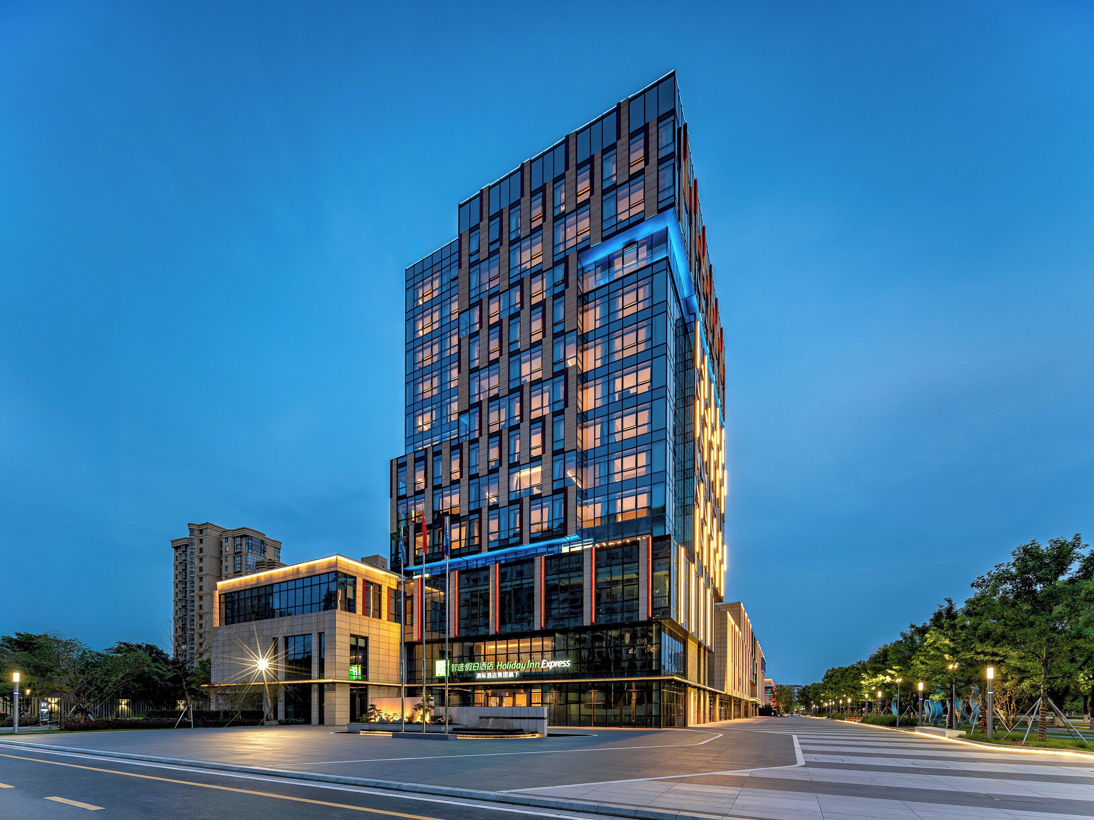 Un hotel moderno con fachada de vidrio, varios pisos y un llamativo letrero de Holiday Inn Express.