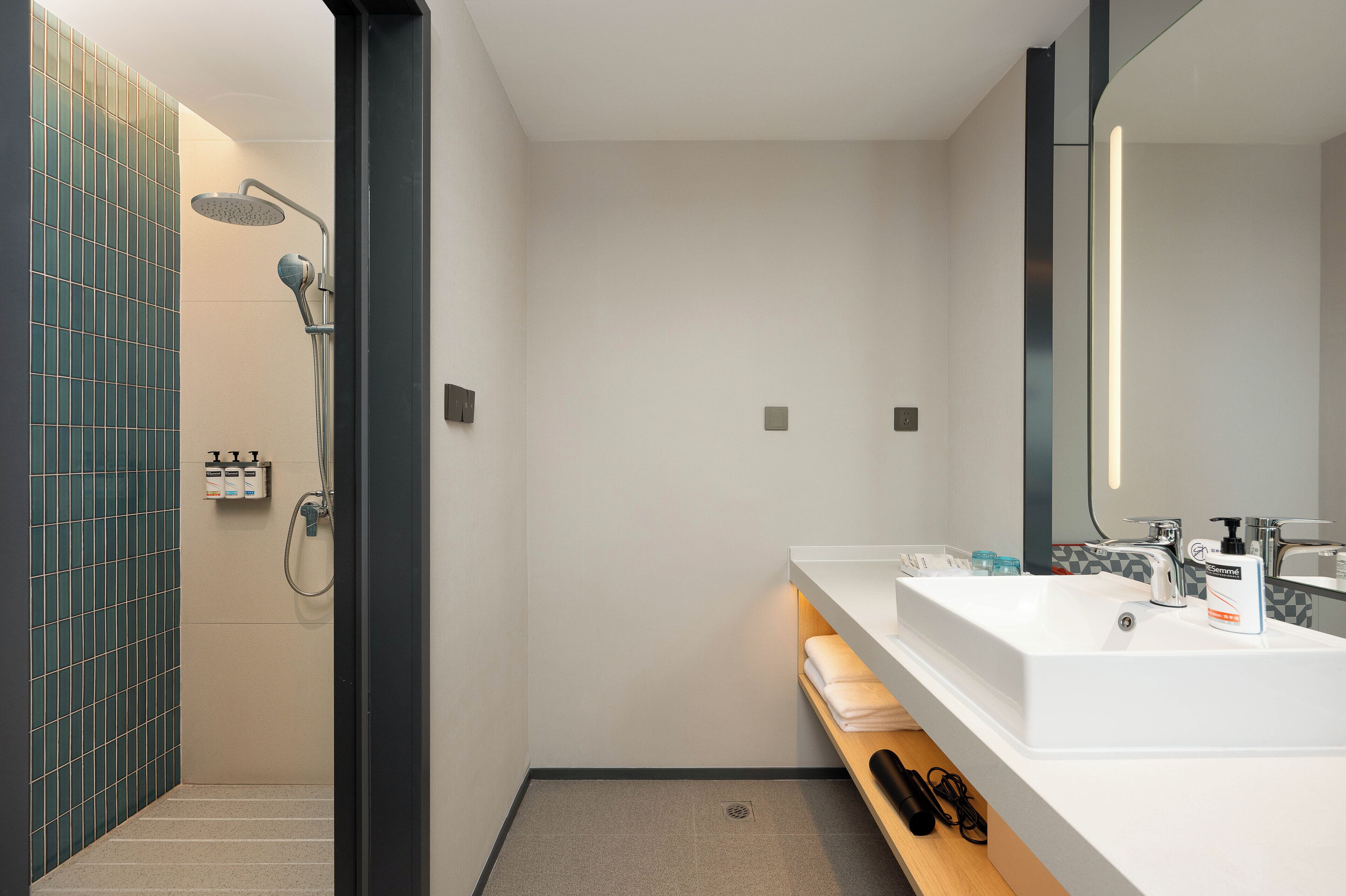 Een moderne badkamer met een douche, wastafel en spiegel.