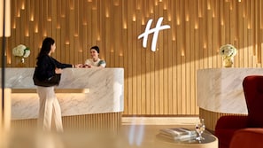 A hotel reception area with wooden paneling, marble reception counters, and a red armchair. - ANA Holiday Inn Tokyo Bay by IHG (Tokyo)