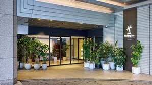 L'ingresso dell'ANA Holiday Inn Tokyo Bay, caratterizzato da un design moderno, ampie vetrate e piante in vaso.