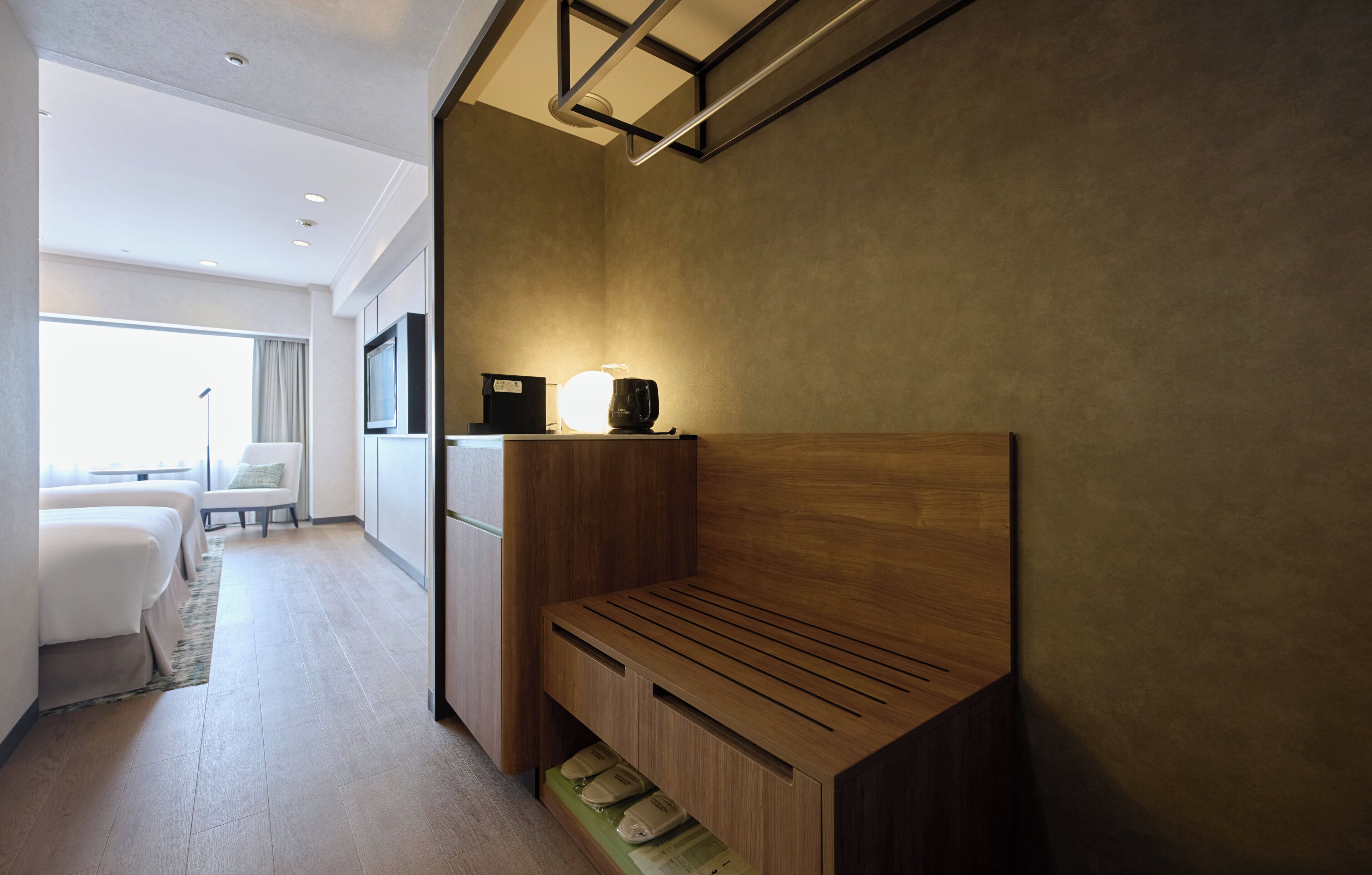 A modern hotel room with a wooden headboard, a bedside table, and a flat-screen TV.