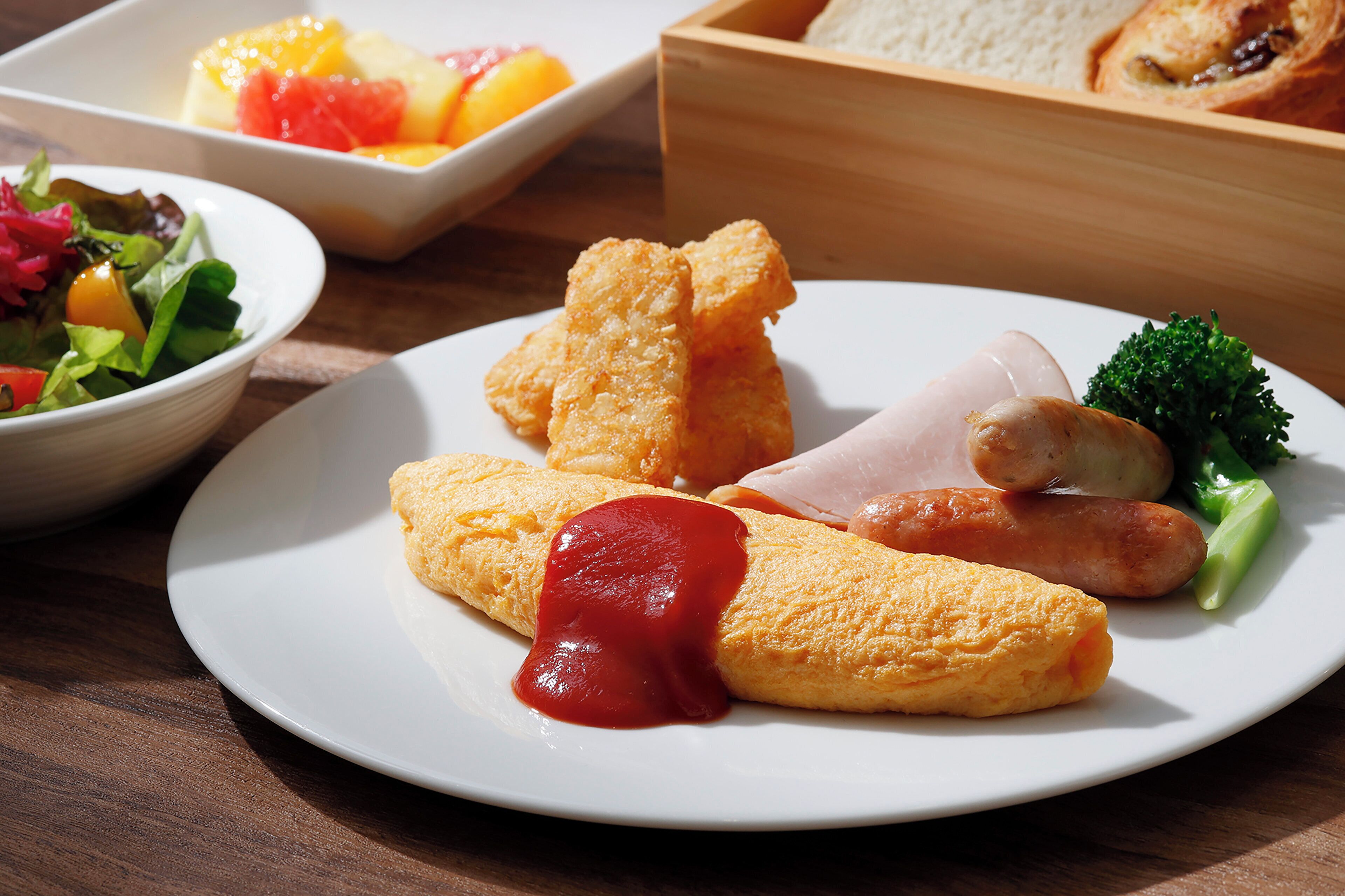 A plate with food items including a rolled omelette, sausages, and vegetables.