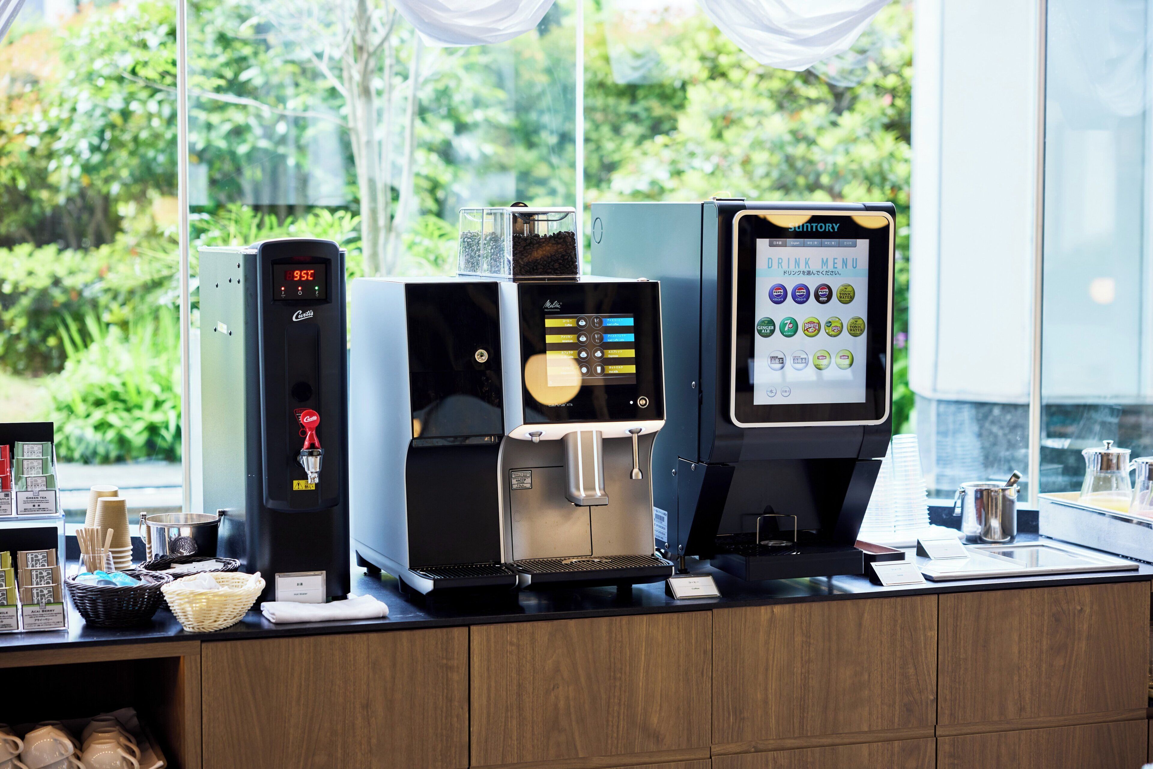 A coffee station with a digital coffee maker, a drip coffee maker, and a drink menu dispenser.