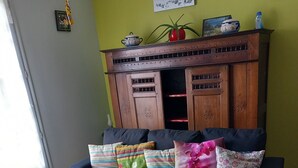 Ein Wohnzimmer mit einem dunkelblauen Sofa, einem Holztisch und einer gemusterten Decke.